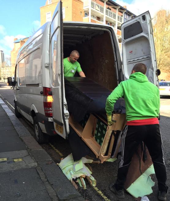 Technicians loading old furniture in a van.