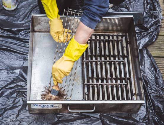 bbq-cleaning Barbecue cleaner working to scrub a used bbq