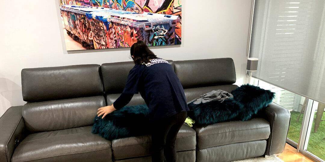 ndis one-off cleaning lady finished cleaning the client's couch and is amidst arranging the cushions