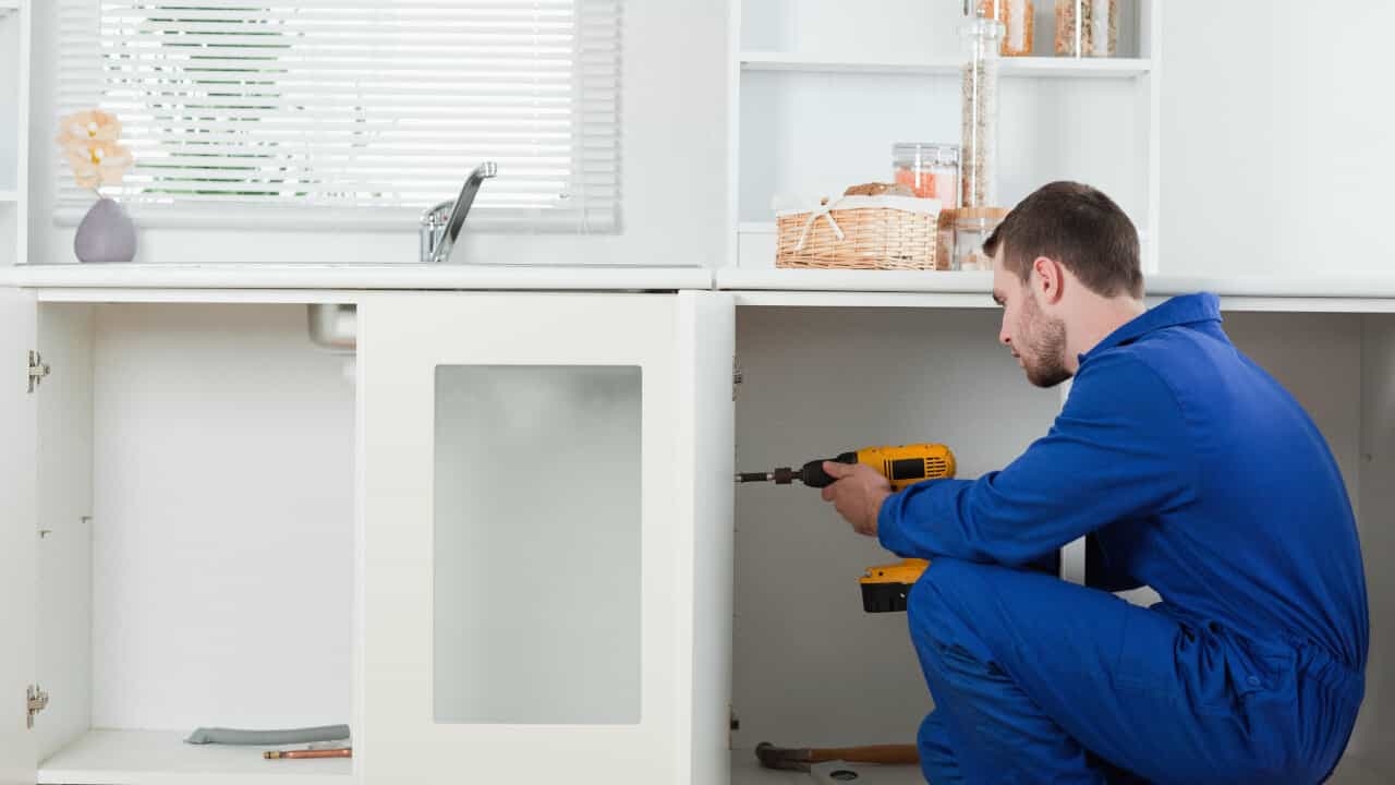 handyman installing doors to kitchen cabinets