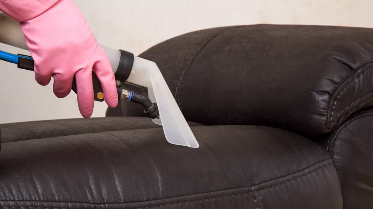 close-up of an ndis cleaner using his machine to clean a sofa